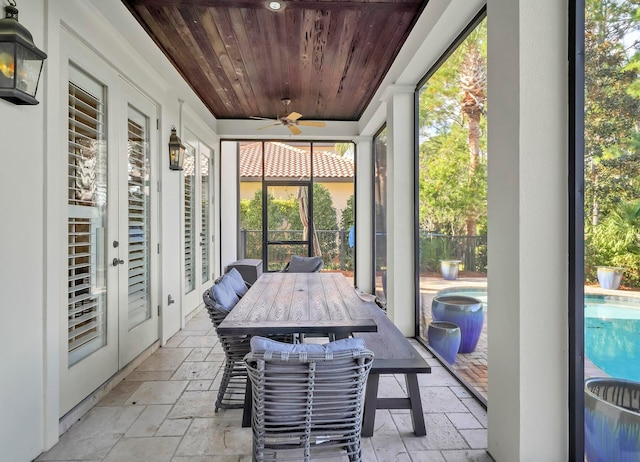 unfurnished sunroom featuring wood ceiling, a wealth of natural light, and ceiling fan