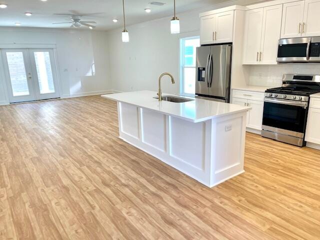 kitchen with sink, appliances with stainless steel finishes, hanging light fixtures, and white cabinetry