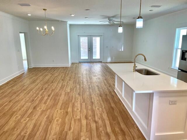 kitchen featuring light hardwood / wood-style flooring, a kitchen island with sink, sink, and pendant lighting