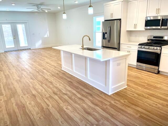 kitchen featuring sink, appliances with stainless steel finishes, decorative light fixtures, and white cabinets