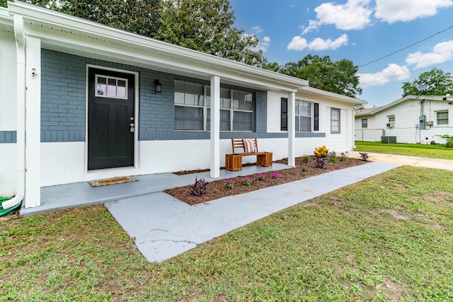 view of front of house featuring a porch, a front lawn, and central air condition unit