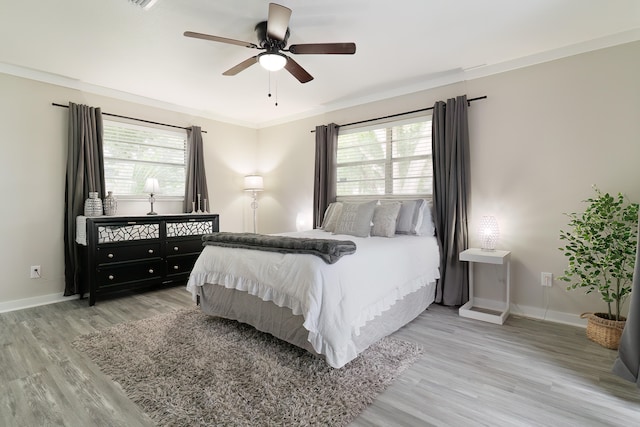 bedroom with multiple windows, ceiling fan, light hardwood / wood-style floors, and ornamental molding