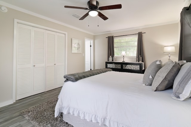 bedroom featuring crown molding, dark wood-type flooring, ceiling fan, and a closet