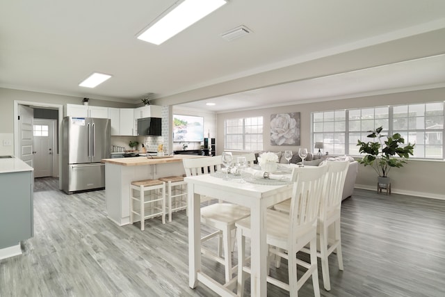 dining space with light hardwood / wood-style floors and crown molding