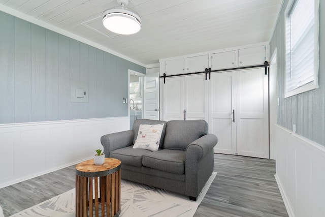 living room with ornamental molding, light hardwood / wood-style flooring, sink, and a barn door