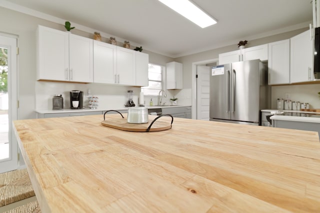 kitchen featuring ornamental molding, white cabinetry, stainless steel refrigerator, and sink