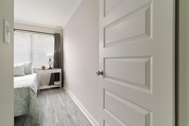 corridor with light wood-type flooring and crown molding