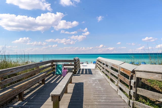 view of dock featuring a water view and a beach view