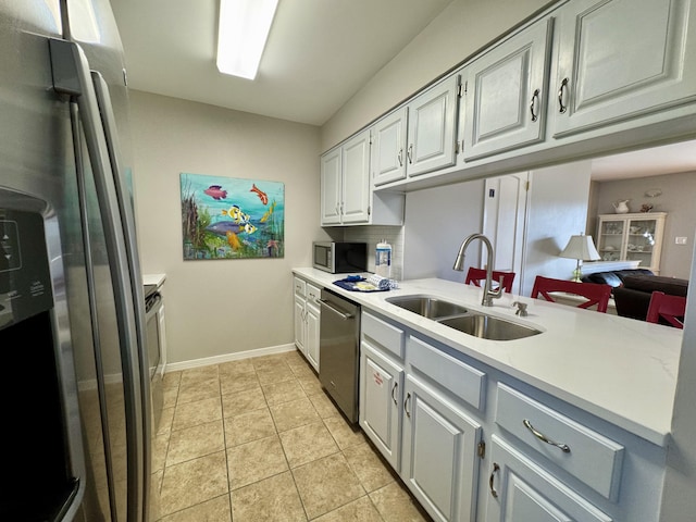 kitchen featuring kitchen peninsula, appliances with stainless steel finishes, sink, white cabinetry, and light tile patterned flooring