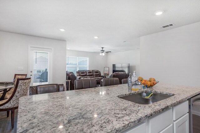 kitchen featuring white cabinets, light stone countertops, sink, wood-type flooring, and ceiling fan