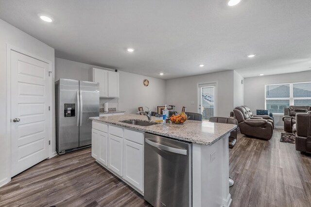 kitchen featuring appliances with stainless steel finishes, white cabinetry, sink, dark wood-type flooring, and a center island with sink