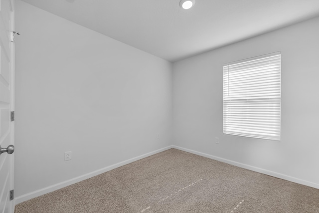 carpeted empty room featuring baseboards