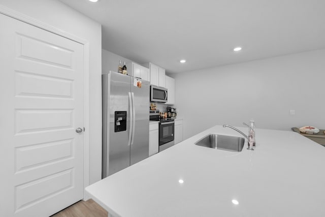kitchen with light countertops, a sink, white cabinetry, stainless steel appliances, and recessed lighting