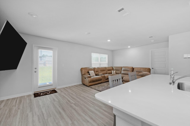 living room featuring plenty of natural light, baseboards, light wood-style floors, and visible vents
