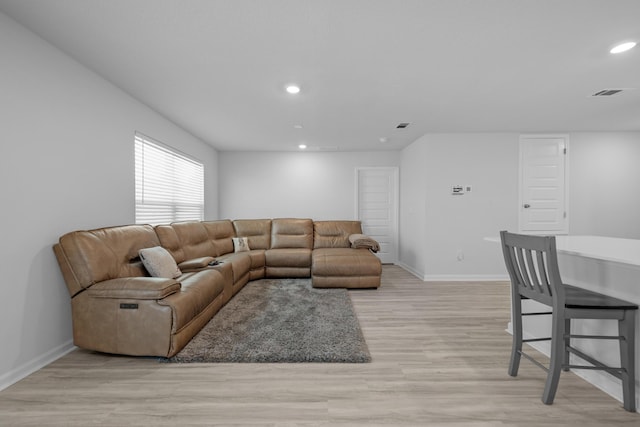 living area featuring baseboards, light wood-type flooring, visible vents, and recessed lighting