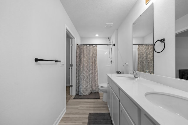 bathroom with toilet, a sink, a textured ceiling, and wood finished floors