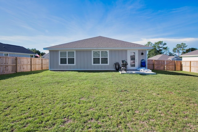 rear view of property with a fenced backyard, roof with shingles, and a lawn