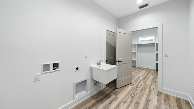 laundry area with hookup for a washing machine, light hardwood / wood-style floors, electric dryer hookup, and sink