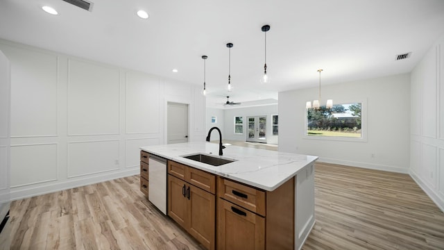 kitchen featuring dishwasher, sink, an island with sink, pendant lighting, and light hardwood / wood-style floors