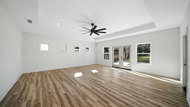 interior space with french doors, light wood-type flooring, a tray ceiling, and ceiling fan