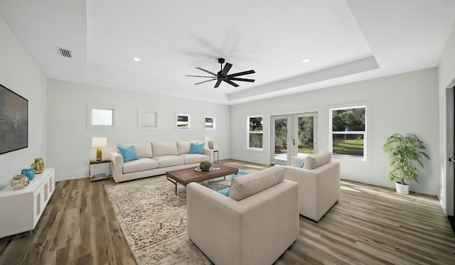 living room featuring wood-type flooring, a raised ceiling, french doors, and ceiling fan