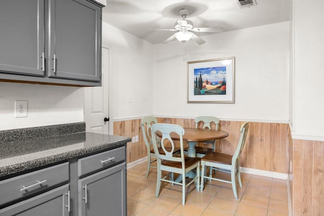 2205 Calle De Marbella, Navarre, FL 32566 - dining space with light tile patterned floors, a ceiling fan, visible vents, wood walls, and wainscoting