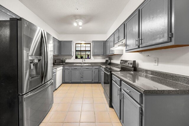 2205 Calle De Marbella, Navarre, FL 32566 - kitchen featuring gray cabinetry, under cabinet range hood, a sink, appliances with stainless steel finishes, and light tile patterned floors