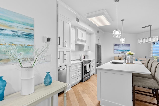 kitchen with appliances with stainless steel finishes, white cabinetry, light hardwood / wood-style flooring, and sink