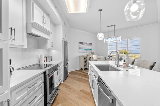 kitchen featuring white cabinets, appliances with stainless steel finishes, hanging light fixtures, and light hardwood / wood-style flooring