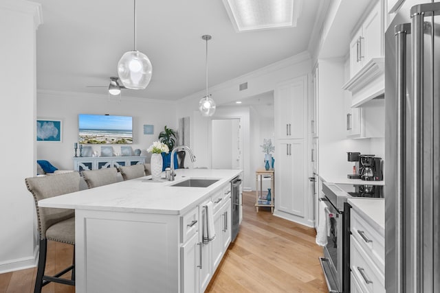 kitchen with light wood-type flooring, stainless steel appliances, white cabinetry, and sink