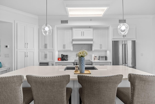 kitchen featuring appliances with stainless steel finishes, a kitchen breakfast bar, a center island with sink, and white cabinetry