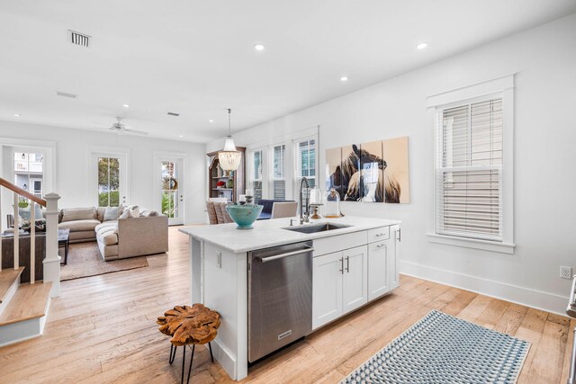 kitchen with hanging light fixtures, sink, white cabinetry, dishwasher, and light hardwood / wood-style floors