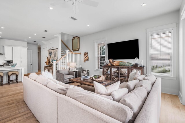 living room featuring ceiling fan, light hardwood / wood-style floors, and a healthy amount of sunlight