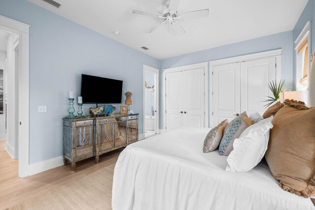 bedroom featuring ceiling fan, two closets, and light hardwood / wood-style floors