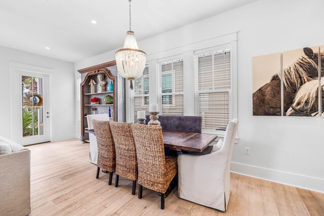 dining space with light hardwood / wood-style flooring and a notable chandelier