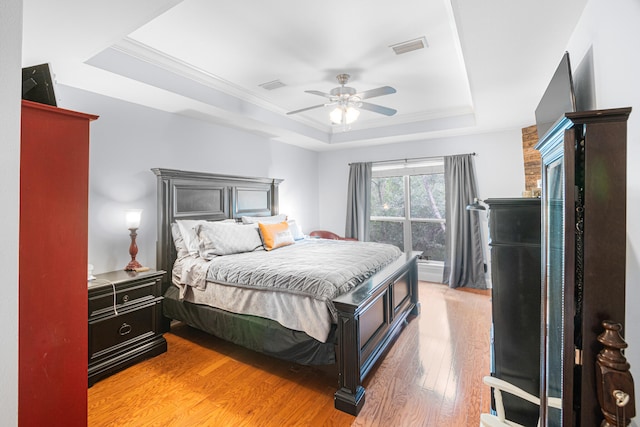 bedroom featuring ceiling fan, hardwood / wood-style floors, and a tray ceiling