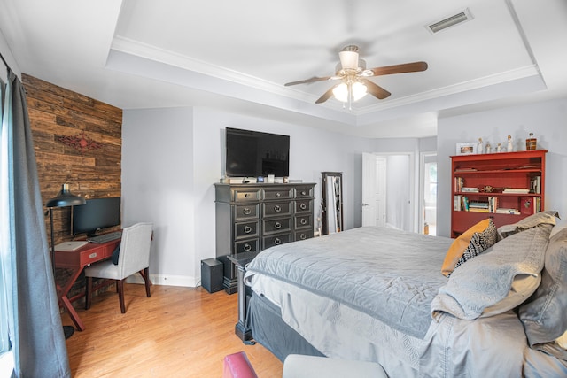 bedroom featuring a tray ceiling, light wood-type flooring, wood walls, and ceiling fan