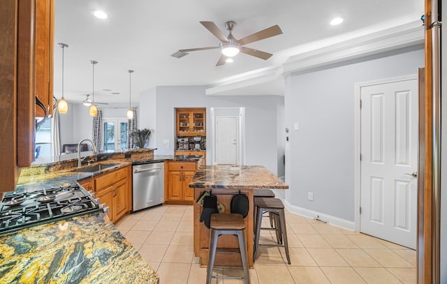 kitchen with dark stone countertops, stainless steel appliances, sink, a kitchen breakfast bar, and ceiling fan