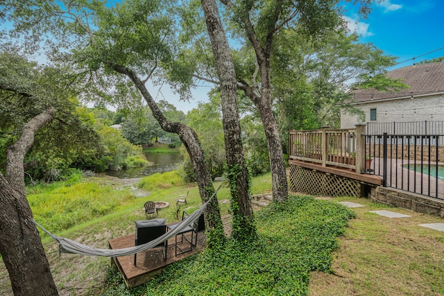 view of yard with a deck with water view and an outdoor fire pit