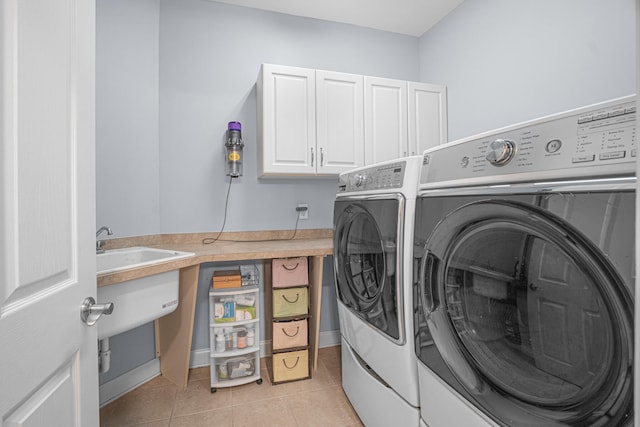 clothes washing area featuring light tile patterned floors, cabinets, and washing machine and dryer