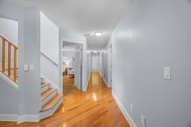 hall with hardwood / wood-style floors and a textured ceiling