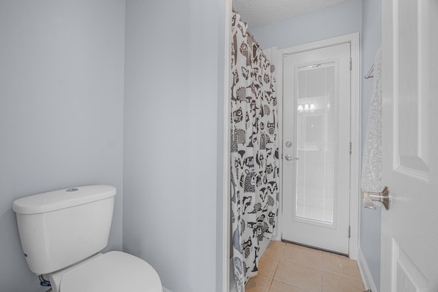 bathroom featuring curtained shower, tile patterned flooring, toilet, and a textured ceiling