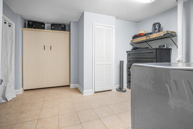 laundry area with a textured ceiling and light tile patterned floors