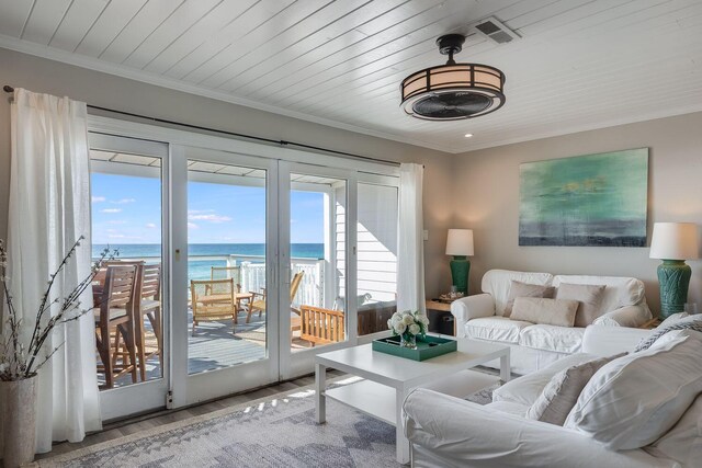 living room featuring a healthy amount of sunlight, a water view, ornamental molding, and hardwood / wood-style flooring