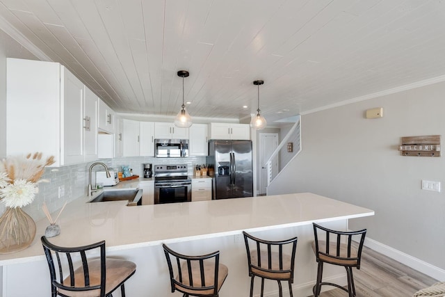 kitchen with light wood-type flooring, sink, kitchen peninsula, hanging light fixtures, and stainless steel appliances