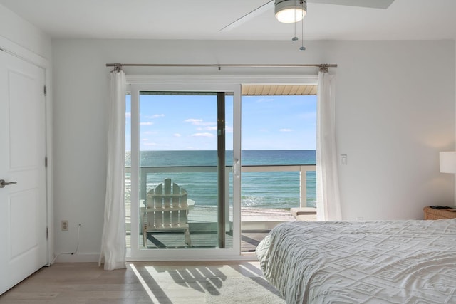 bedroom featuring a water view, a beach view, access to exterior, ceiling fan, and hardwood / wood-style floors