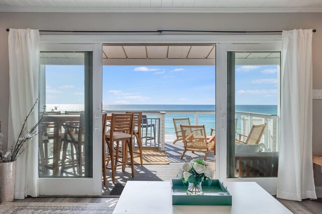 dining area featuring ornamental molding, hardwood / wood-style floors, a water view, and a view of the beach