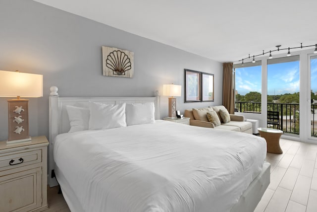 bedroom featuring track lighting, access to exterior, and light hardwood / wood-style flooring