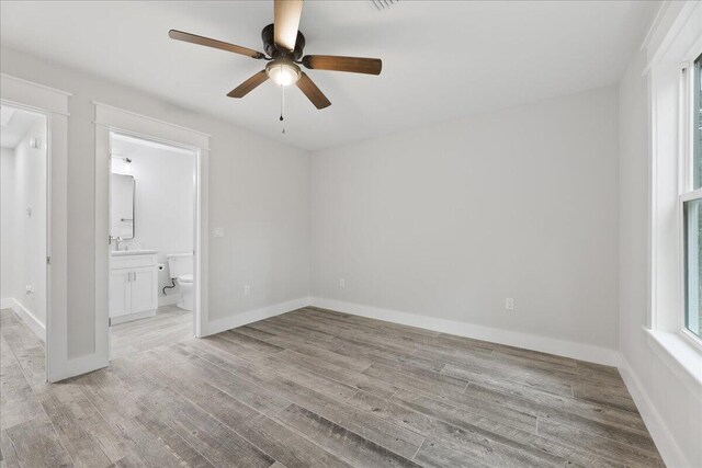 unfurnished bedroom with ceiling fan, connected bathroom, and light hardwood / wood-style flooring