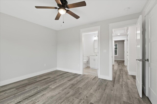 unfurnished bedroom with ceiling fan, ensuite bathroom, and light wood-type flooring